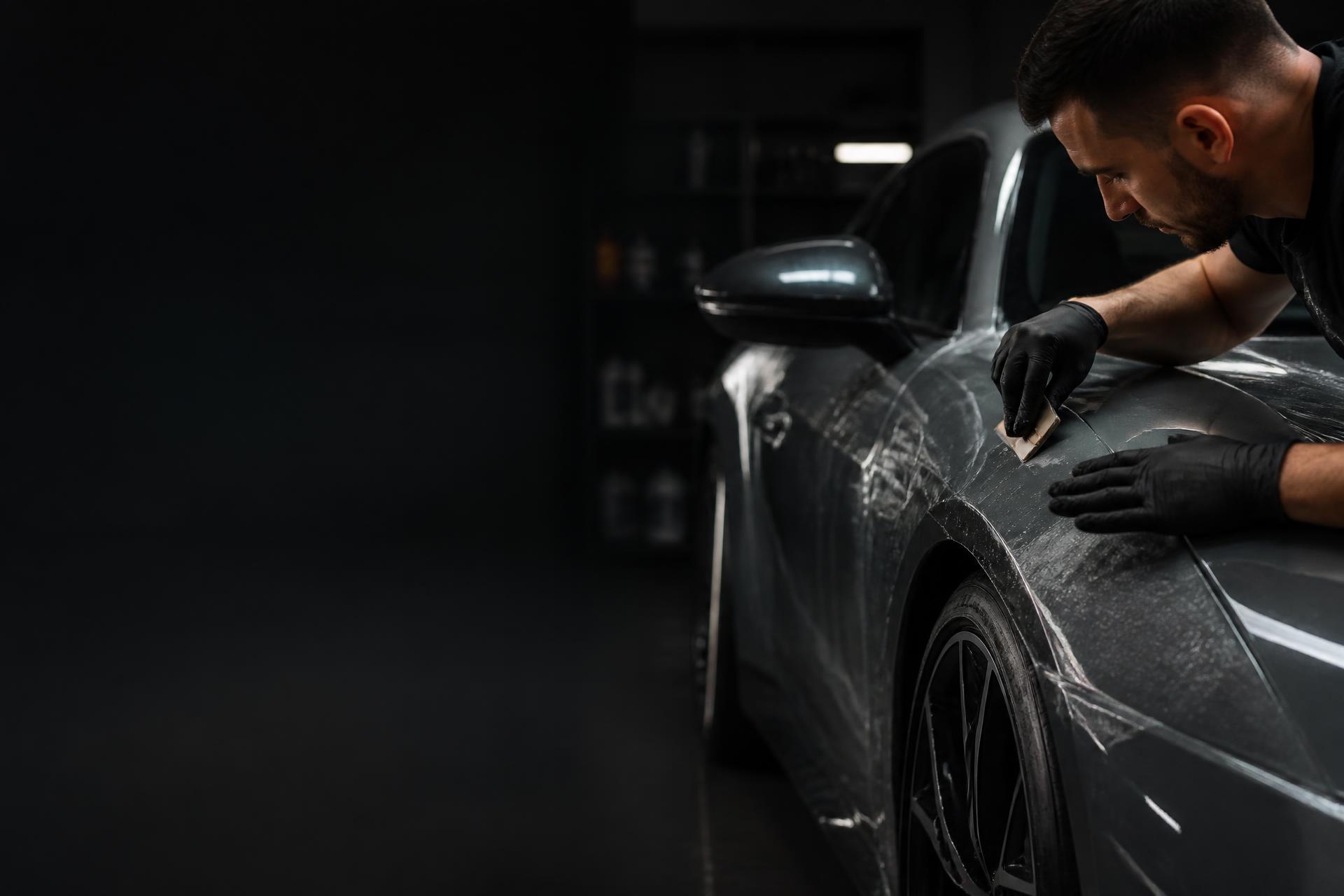 Specialist Detailing Studio aplicând folie de protecție PPF pe caroseria unei mașini sport